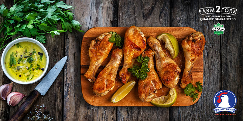 A board of Crunchy Potato Chip Drumsticks with lemon wedges garnished with coriander | Country Choice Chicken Drumsticks